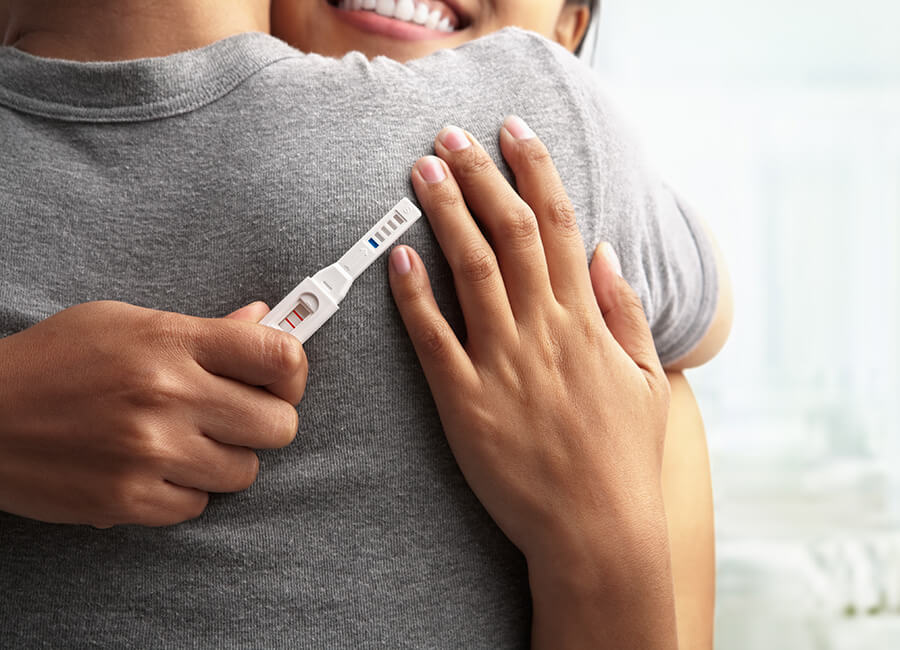 Couple hugging and holding a pregnancy test