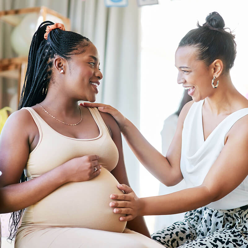 woman touching another woman's pregnant belly